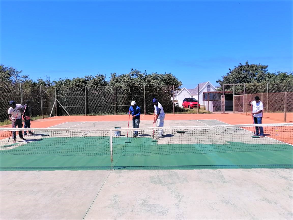 Painters applying paint on tennis court